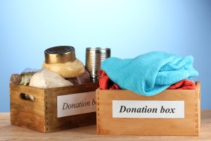 Donation boxes with clothing and food on blue background close-u