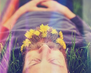 a sleeping hipster lying in tall grass with dandelions in his ep