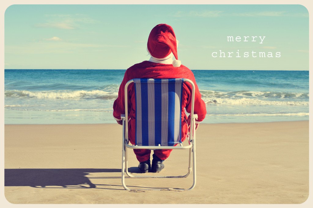 a picture of santa claus sitting in a beach chair on the beach a