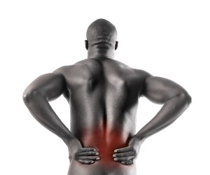 A person with a muscular build holds their lower back, displaying a reddish area indicative of chronic pain. They're likely exploring resources for understanding chronic pain to better manage their discomfort.