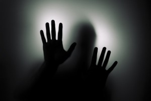 A silhouette of a person pressing hands against a frosted glass surface, encapsulating the silent struggle and resilience in finding CRPS coping techniques.