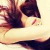 A woman with long brown hair lies down, partially covering her face with her arm, reflecting on self-care practices for chronic pain.