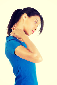 A woman in a blue shirt holds her neck with both hands, tilting her head to one side, demonstrating coping strategies for chronic pain relief.