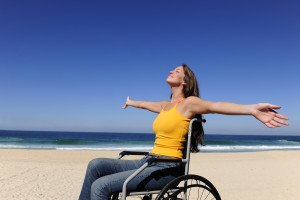 Woman In Wheelchair Enjoying Summer Vacation On The Beach