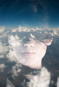 A woman's face is overlaid with a cloudy sky, seamlessly blending her features with the clouds, much like exploring self-help resources for chronic illness to find clarity amidst life's storms.