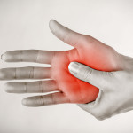 A person holds their hand with the palm highlighted in red, indicating pain or discomfort, a common symptom of CRPS.