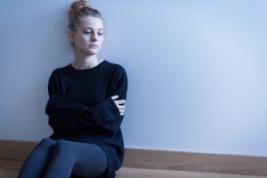 Young woman with anxiety disorder sitting on the floor