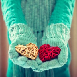 Woman hands in light teal knitted mittens are holding a beautifu