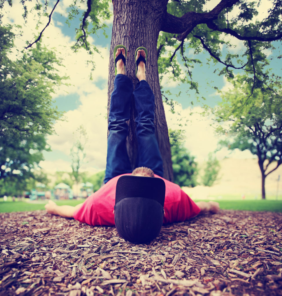 a man with his feet resting on a tree trunk during summer toned | The ...